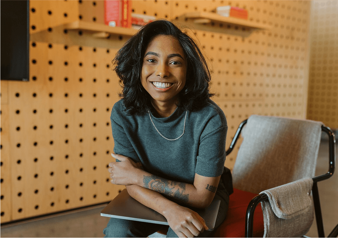person smiling at camera with laptop in hand