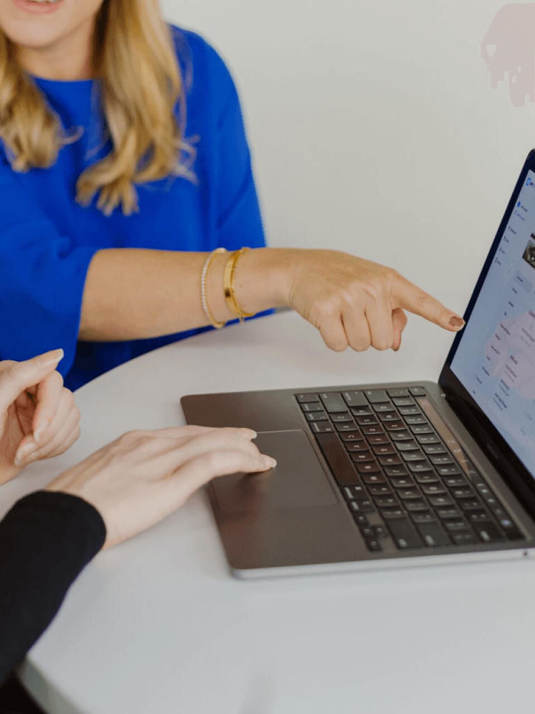 two people pointing at laptop and talking